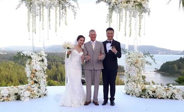 Wedding couple with Peter Notley beneath a floral ceremony arch in Phuket