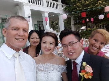 Peter Notley with a newly married couple and wedding guests in Phuket