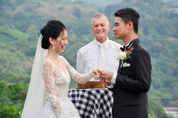 Couple exchanging rings with Peter Notley during a Phuket ceremony
